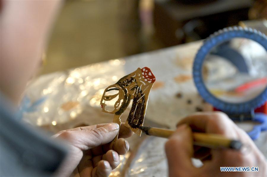 Zhou Zhibing, the apprentice of Pan Mingsheng, applies dye to the shadow puppet at Xinzhai Township of Weiyuan County in Dingxi City, northwest China\'s Gansu province, March 13, 2019. Many local folk artists concentrate on inheriting and passing down the folk art of shadow puppet performing and making in Gansu. They devote themselves to the study of the art and also organize various events to popularize the art. (Xinhua/Li Xiao)