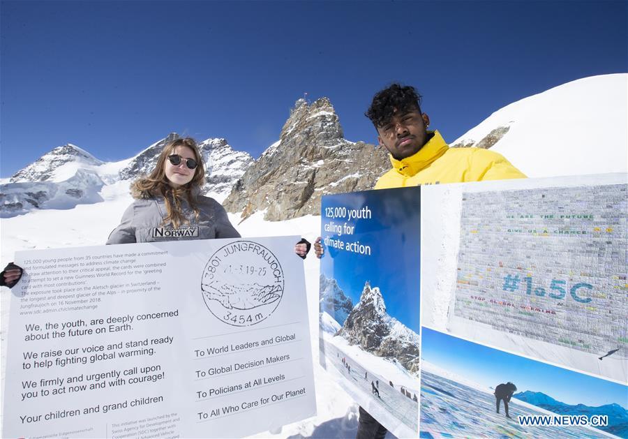 Swiss teenagers Sarangan Sivarajalingam (R) and Selma Schellenberg show copies of a postcard calling for action against climate change on the Aletsch glacier under Jungfraujoch in Switzerland, on March 20, 2019. Some 900 postcards from youths all over the world were stamped and sent on Wednesday from Europe\'s highest postbox on the Jungfraujoch peak, Switzerland, to global leaders, calling for action against climate change. (Xinhua/Xu Jinq