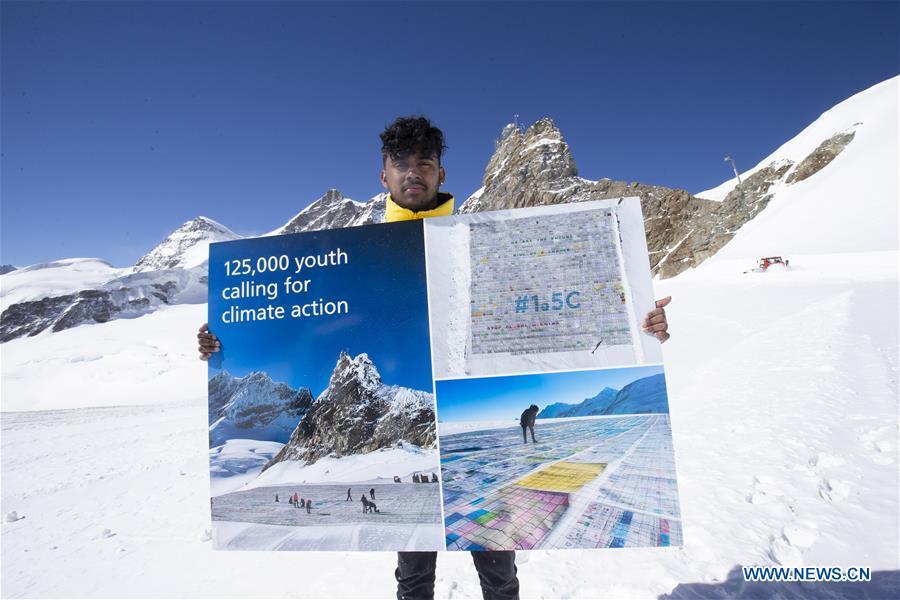 Swiss teenager Sarangan Sivarajalingam shows a copy of a postcard calling for action against climate change on the Aletsch glacier under Jungfraujoch in Switzerland, on March 20, 2019. Some 900 postcards from youths all over the world were stamped and sent on Wednesday from Europe\'s highest postbox on the Jungfraujoch peak, Switzerland, to global leaders, calling for action against climate change. (Xinhua/Xu Jinquan)