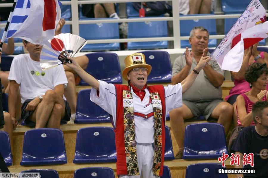 Naotoshi Yamada of Japan flies a Japanese flag while Japanese table tennis player Ai Fukuhara plays against Miao Miao of Australia at the 2004 Olympic Games in Athens, Saturday, Aug. 7, 2004. Japan\'s \