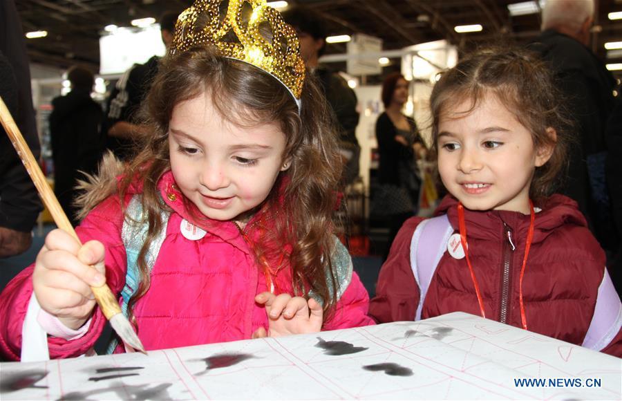 A little girl tries Chinese calligraphy at the Chinese exhibition area of the 2019 Paris book fair in Paris, capital of France, on March 15, 2019. (Xinhua/Yang Yimiao)