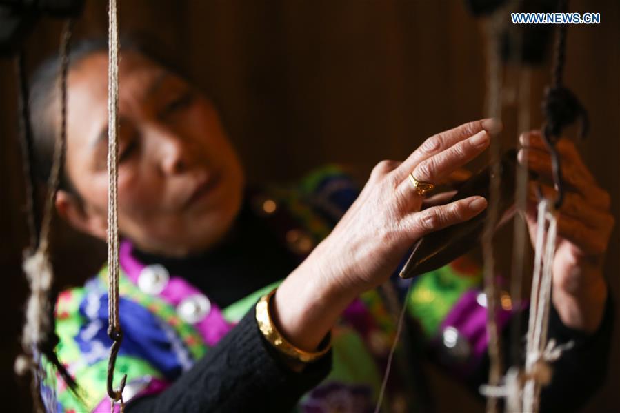 A woman of Dong ethnic group arranges the shuttle of the loom at Laozhai Village of Yuping Dong Autonomous county of Tongren, southwest China\'s Guizhou Province, March 23, 2019. Traditional Dong cloth making has a long history. The procedure includes planting cotton, spinning, weaving, dyeing, etc. And the cloth enjoys lasting popularity among the people of Dong ethnic group. (Xinhua/Luo Dafu)