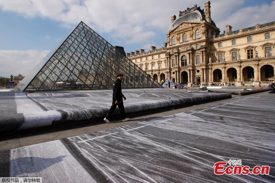 French artist JR works in the courtyard of the Louvre Museum near the glass pyramid designed by Ieoh Ming Pei as the Louvre Museum celebrates the 30th anniversary of its glass pyramid in Paris, France, March 26, 2019.  (Photo/Agencies)