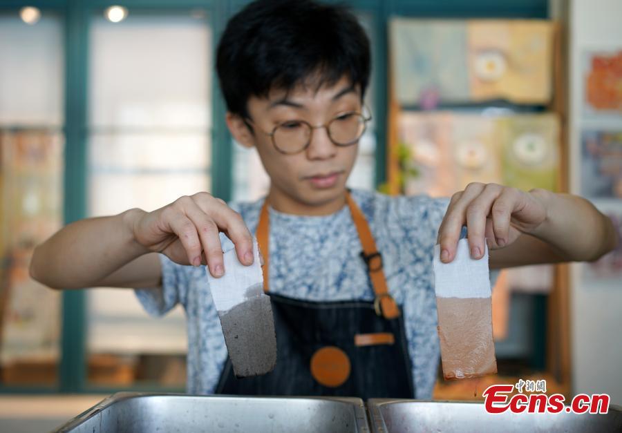 Eric Cheung, founder of Dyelicious, compares the colors made from materials such as leftover food and plants in Hong Kong. (Photo: China News Service/Zhang Wei)