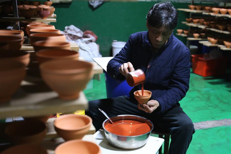 Wu Lizhu, inheritor of the workmanship of Jianzhan teaware, glazes a piece of porcelain at his workshop in Jianyang District of Nanping City, south China\'s Fujian Province, March 28, 2019. Jianzhan teaware, a well-known Chinese porcelain originated in Jianyang, dates back to more than 1,000 years ago in Song dynasty (960-1279). It was the best teaware for scholars and literati to use during that time in tea competitions. Jianzhan teawares are known for their variability. Glazes can range in color from dark plum to yellow, green, and blue. During the heating and cooling processes, iron element in the clay can migrate within the glaze to form surface crystals in rich and glossy colors, as in the \