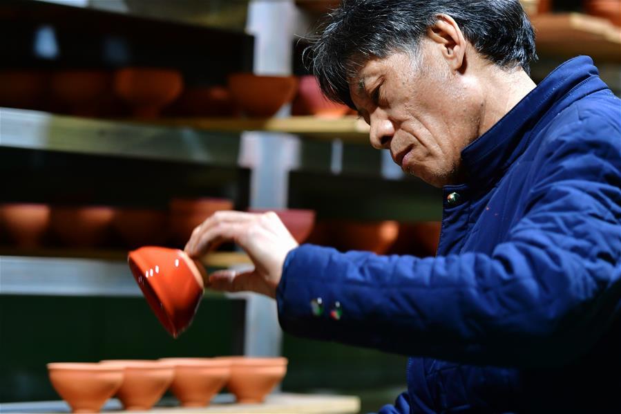 Wu Lizhu, inheritor of the workmanship of Jianzhan teaware, glazes a piece of porcelain at his workshop in Jianyang District of Nanping City, south China\'s Fujian Province, March 28, 2019. Jianzhan teaware, a well-known Chinese porcelain originated in Jianyang, dates back to more than 1,000 years ago in Song dynasty (960-1279). It was the best teaware for scholars and literati to use during that time in tea competitions. Jianzhan teawares are known for their variability. Glazes can range in color from dark plum to yellow, green, and blue. During the heating and cooling processes, iron element in the clay can migrate within the glaze to form surface crystals in rich and glossy colors, as in the \