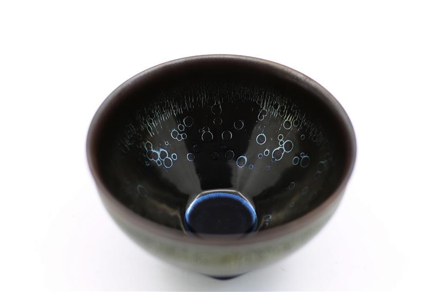 Photo taken on March 28, 2019 shows a piece of porcelain made by Wu Lizhu, inheritor of the workmanship of Jianzhan teaware, at his workshop in Jianyang District of Nanping City, south China\'s Fujian Province. Jianzhan teaware, a well-known Chinese porcelain originated in Jianyang, dates back to more than 1,000 years ago in Song dynasty (960-1279). It was the best teaware for scholars and literati to use during that time in tea competitions. Jianzhan teawares are known for their variability. Glazes can range in color from dark plum to yellow, green, and blue. During the heating and cooling processes, iron element in the clay can migrate within the glaze to form surface crystals in rich and glossy colors, as in the \