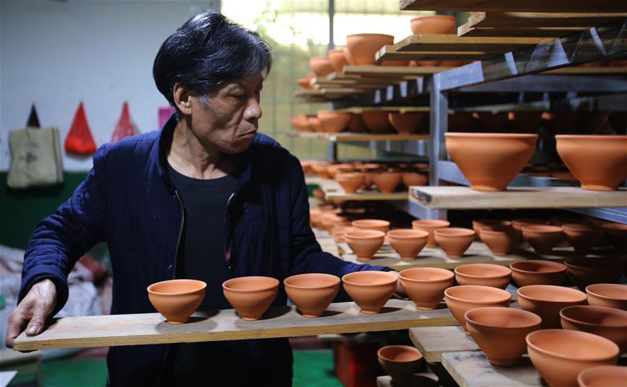 Wu Lizhu, inheritor of the workmanship of Jianzhan teaware, carries pieces of porcelain at his workshop in Jianyang District of Nanping City, south China\'s Fujian Province, March 28, 2019. Jianzhan teaware, a well-known Chinese porcelain originated in Jianyang, dates back to more than 1,000 years ago in Song dynasty (960-1279). It was the best teaware for scholars and literati to use during that time in tea competitions. Jianzhan teawares are known for their variability. Glazes can range in color from dark plum to yellow, green, and blue. During the heating and cooling processes, iron element in the clay can migrate within the glaze to form surface crystals in rich and glossy colors, as in the \