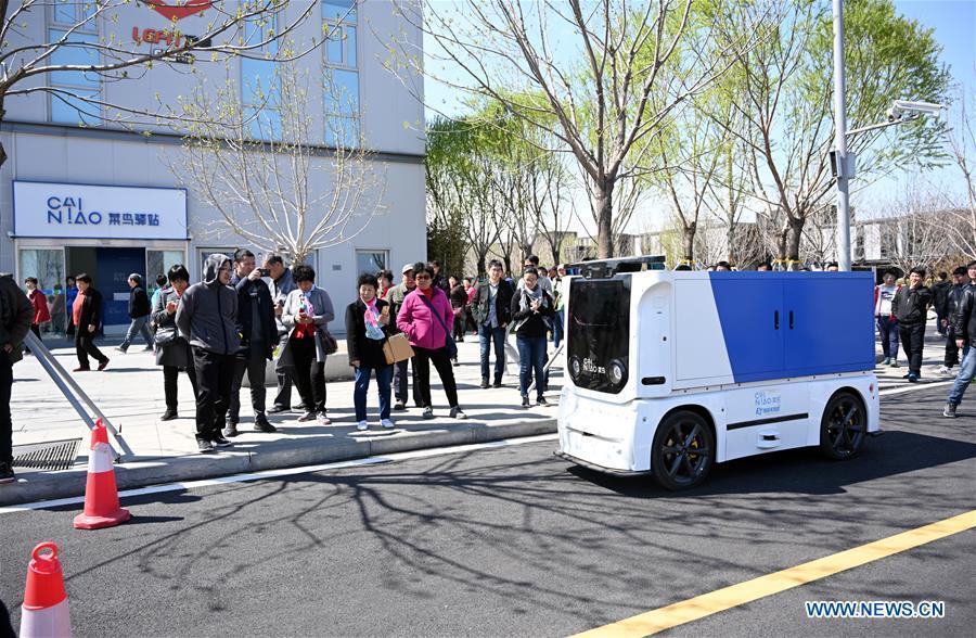 An unmanned express delivery vehicle runs on the street of Xiongan citizen service center in Xiongan New Area, north China\'s Hebei Province on March 31, 2019. The unmanned express delivery vehicle, independently researched and developed by Cainiao Network, Alibaba\'s logistics arm, was recently put into service at Xiongan citizen service center. The new energy vehicle can convey about 200 small packages at one time from delivery station to intelligent cabinet. (Xinhua/Jin Liangkuai)