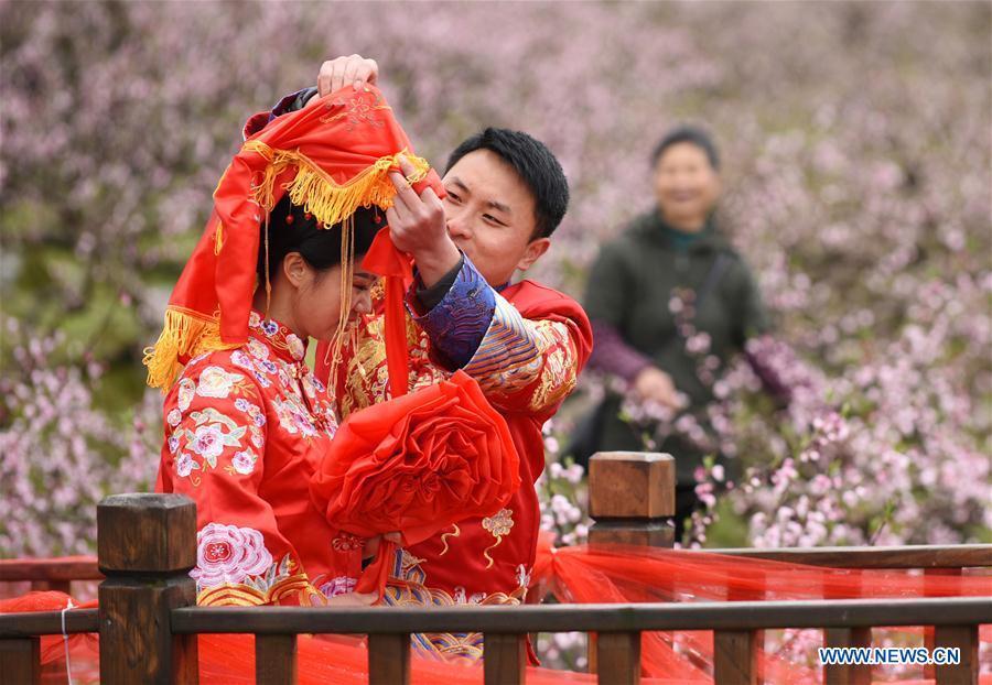 A groom arranges red bridal veil for his bride during a group wedding ceremony in traditional style in Wude Town of Shiqian County, southwest China\'s Guizhou Province, April 4, 2019. A group wedding ceremony in traditional style was held here Thursday for couples who have been striving on the frontline for the county\'s fight against poverty. (Xinhua/Yang Wenbin)