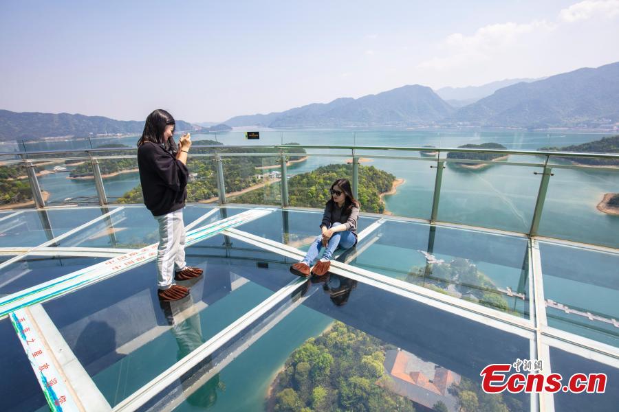 Tourists take photos on the platform of a glass sightseeing tower, 99 meters above the ground, in Lushan Xihai scenic area in Yongxiu County, East China\'s Jiangxi Province, April 7, 2019. Visitors to the tower can enjoy great views of the mountain and lake. (Photo: China News Service/Zhang Haiyan)