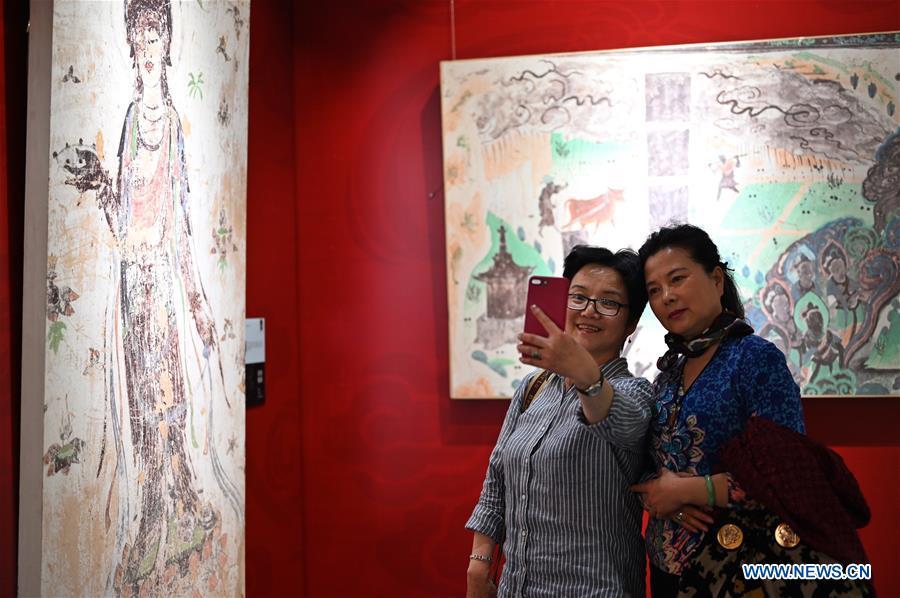 Visitors pose for a group photo during a Dunhuang fresco itinerant exhibition in Yunnan University in Kunming, southwest China\'s Yunnan Province, April 10, 2019. A Dunhuang fresco itinerant exhibition, with the participation of nearly 50 frescoes, was held in Yunnan University in Kunming Wednesday. (Xinhua/Qin Qing)