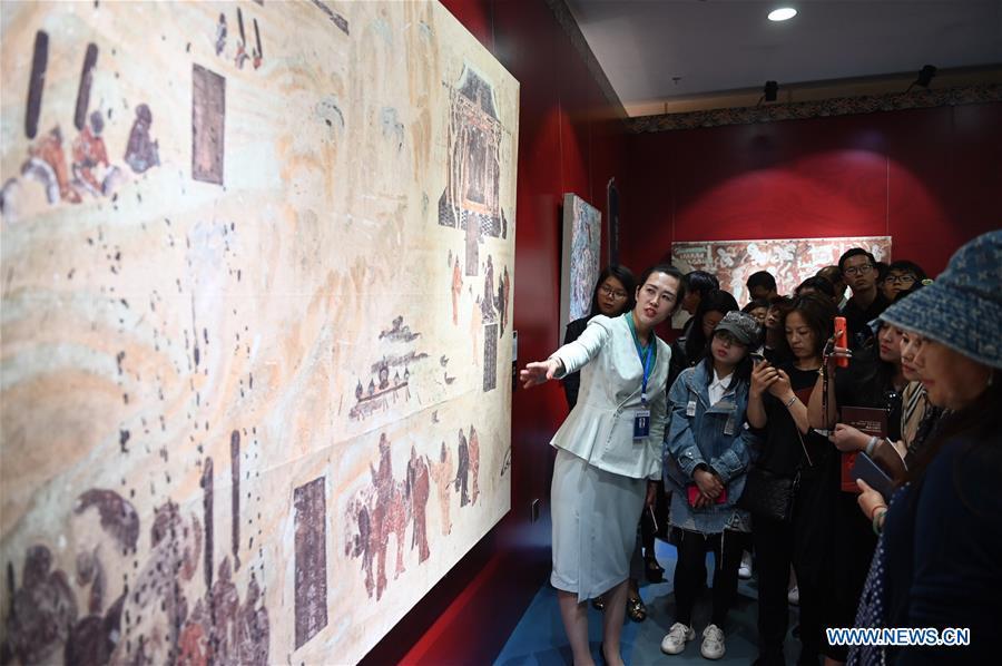 Ma Lin(L), a guide from Dunhuang Academy China, explains fresco culture to visitors during a Dunhuang fresco itinerant exhibition in Yunnan University in Kunming, southwest China\'s Yunnan Province, April 10, 2019. A Dunhuang fresco itinerant exhibition, with the participation of nearly 50 frescoes, was held in Yunnan University in Kunming Wednesday. (Xinhua/Qin Qing)