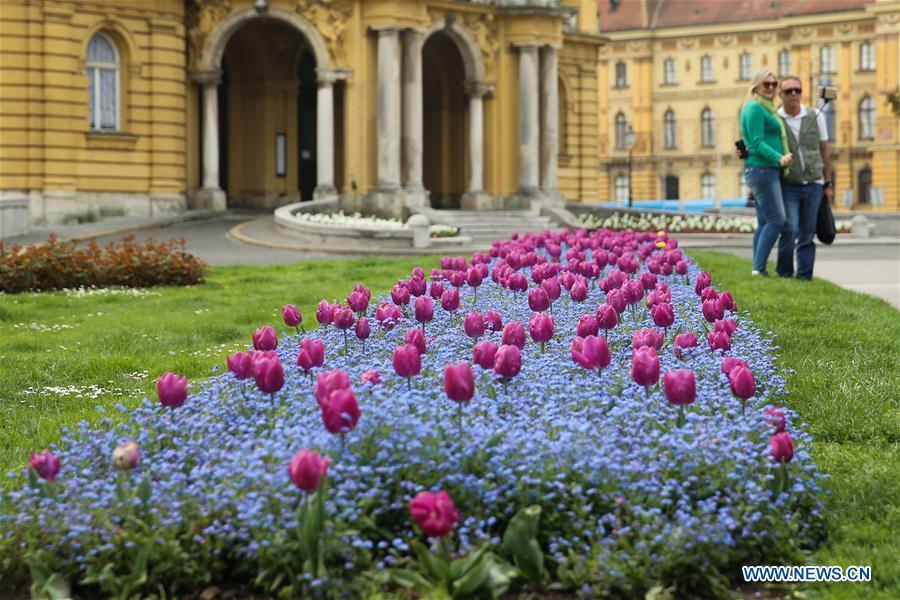 Photo taken on April 10, 2019 shows tourists taking photos with flowers outside the Croatian National Theatre in downtown Zagreb, capital of Croatia. (Xinhua/Zheng Huansong)
