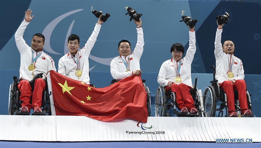 File photo taken on March 17, 2018 shows gold medalists, China\'s Wang Haitao, Chen Jianxin, Liu Wei, Wang Meng and Zhang Qiang (L to R) celebrating on the podium during the awarding ceremony for wheelchair curling at the 2018 PyeongChang Winter Paralympic Games at Gangneung, South Korea. China beat Norway in the final 6-5 to claim the title of the event, which is also China\'s first-ever Winter Paralympic medal with gold. From sending athletes to Helsinki Summer Olympic Games for the very first time in 1952 to winning the bid to host 2022 Winter Olympic Games in 2015, the People\'s Republic of China went through a remarkable history of sports, including successfully hosting the 2008 Summer Olympic Games and preparing for the upcoming 2022 Winter Olympic Games. (Xinhua/Xia Yifang)