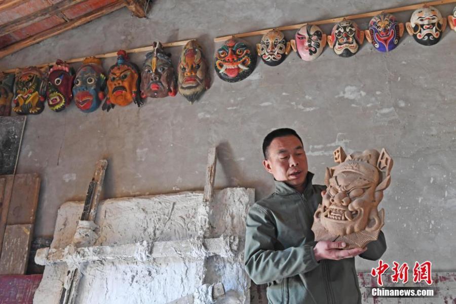 Ma Lande shows masks of the Nuo Opera at his studio in Lanzhou City, Northwest China\'s Gansu Province, April 14, 2019. The handicraftsman said he has made more than 2,000 Nuo Opera masks in the past 17 years, depicting a broad range of topics, including mythical figures from Chinese legends and classic novels. Masks, usually carved out of willow or camphor wood, are an important part of Nuo Opera, an ancient folk drama still popular in some parts of China. The purpose of Nuo Opera is to drive away devils, disease and evil influences, and also to petition the gods for their blessings. (Photo: China News Service/Yang Yanmin)