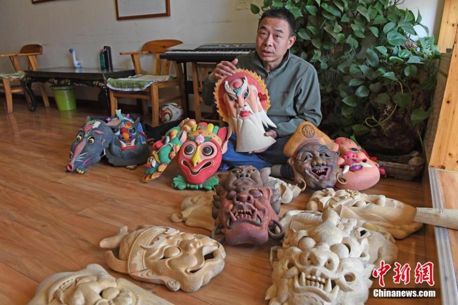 Ma Lande shows masks of the Nuo Opera at his studio in Lanzhou City, Northwest China\'s Gansu Province, April 14, 2019. The handicraftsman said he has made more than 2,000 Nuo Opera masks in the past 17 years, depicting a broad range of topics, including mythical figures from Chinese legends and classic novels. Masks, usually carved out of willow or camphor wood, are an important part of Nuo Opera, an ancient folk drama still popular in some parts of China. The purpose of Nuo Opera is to drive away devils, disease and evil influences, and also to petition the gods for their blessings. (Photo: China News Service/Yang Yanmin)