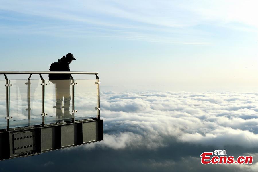 A photographer looks at clouds surrounding Mount Sanqing in Jiangxi Province. (Photo: China News Service/Zhang Hezhong)