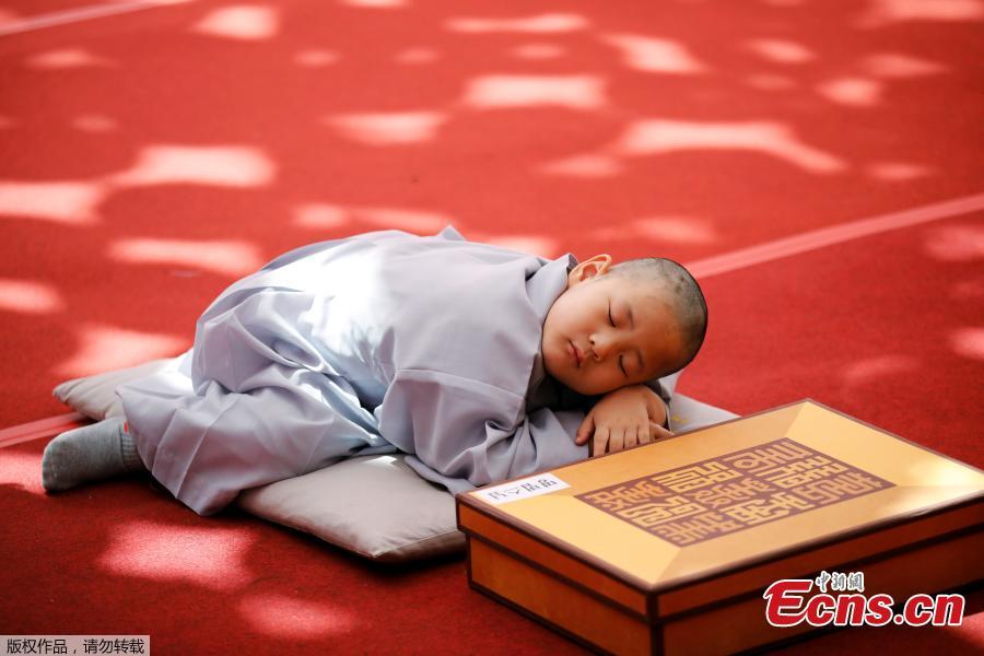 A boy sleeps on the ground after having his head shaved during the \'Children becoming Buddhist monks\' ceremony at the Jogyesa temple in Seoul, South Korea, April 22, 2019.  South Korean Buddhists prepare to celebrate Buddha\'s upcoming birthday on May 12, 2019.  (Photo/Agencies)