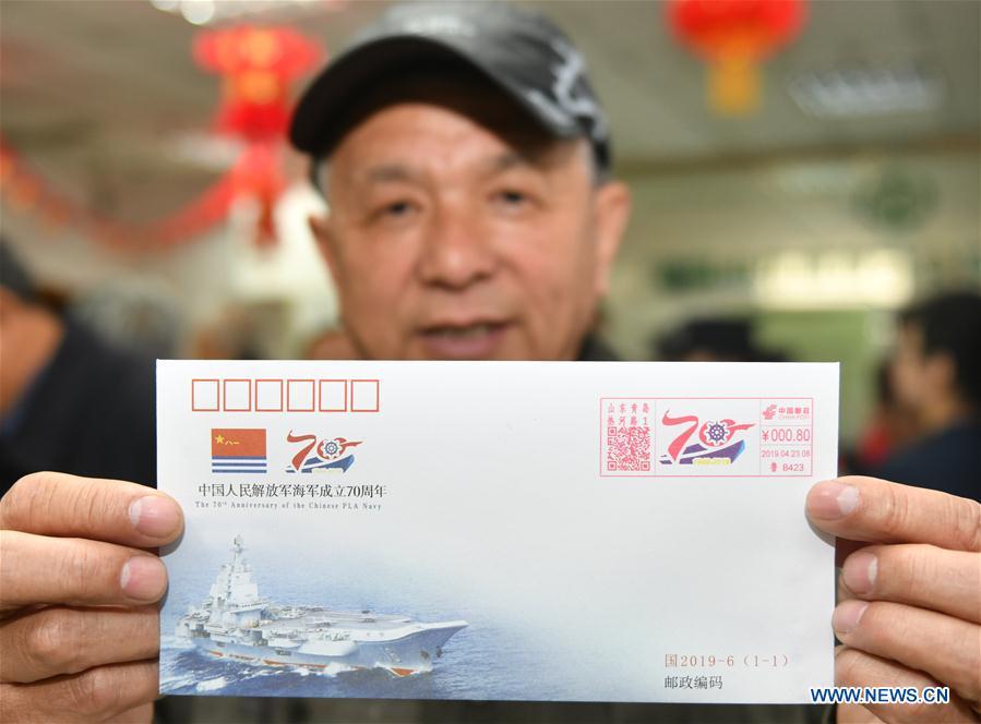 67-year-old Dai Chunguang displays a commemorative envelope at a shop in Qingdao, east China\'s Shandong Province, April 23, 2019. A set of philatelic items were issued on Tuesday to mark the 70th founding anniversary of the Chinese People\'s Liberation Army (PLA) Navy. (Xinhua/Zhu Zheng)