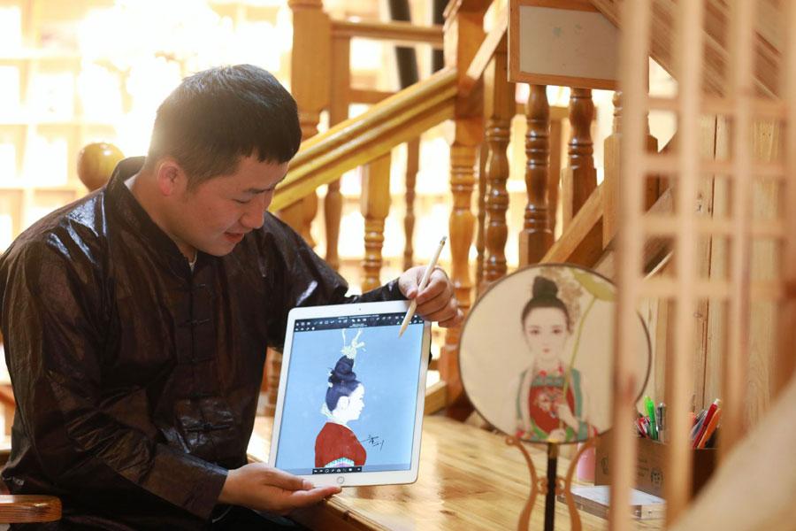Lan Caisheng shows a drawing of a woman dressed in Dong ethnic clothes at the gallery in Zhaoxing Dong village, Liping county, Southwest China\'s Guizhou Province, April 16, 2019. (Photo/Xinhua)