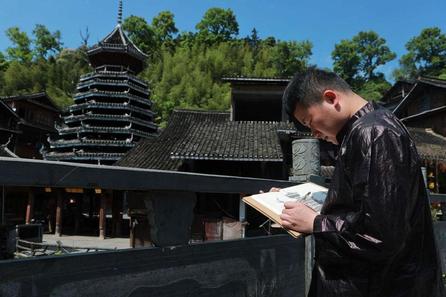 Lan Caisheng draws a Dong building in Zhaoxing Dong village, Liping county, Southwest China\'s Guizhou Province, April 16, 2019. (Photo/Xinhua)
