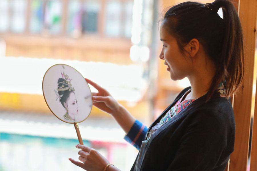 A Dong woman looks at a drawing by Lan Caisheng in Zhaoxing Dong village, Liping county, Southwest China\'s Guizhou Province, April 16, 2019. (Photo/Xinhua)
