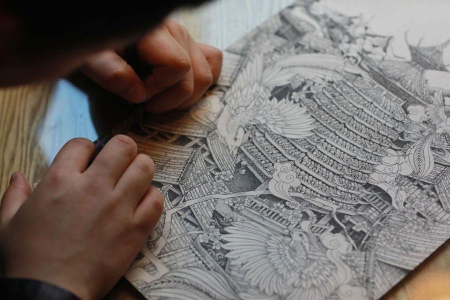 Lan Caisheng draws a Dong-style building at the illustration gallery in Zhaoxing Dong village, Liping county, Southwest China\'s Guizhou Province, April 16, 2019. (Photo/Xinhua)