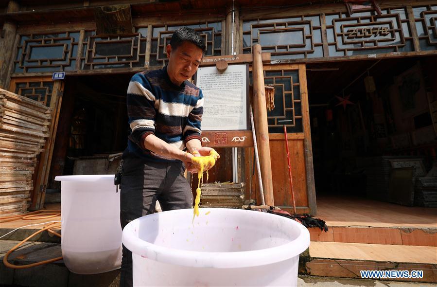Wang Xingwu, a papermaker, checks colored paper pulp made from plants at a workshop in Shiqiao Village of Danzhai County, southwest China\'s Guizhou Province, April 24, 2019. Wang Xingwu, 53, a national intangible cultural heritage inheritor in papermaking, learned the papermaking technique from his family as a child. Besides exerting the old papermaking technique to its full potential, Wang keeps raising product quality and improving the making procedure. With the involvement of plants in the papermaking process, he has created more than 160 kinds of patterned papers and paper crafts. He also develops a kind of handmade white paper more suitable for writing calligraphy and painting. (Xinhua/Huang Xiaohai)