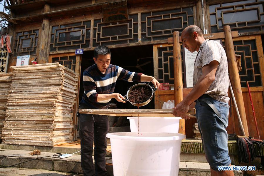 Wang Xingwu (L), a papermaker, filters the plant dyestuff into paper pulp in Shiqiao Village of Danzhai County, southwest China\'s Guizhou Province, April 24, 2019. Wang Xingwu, 53, a national intangible cultural heritage inheritor in papermaking, learned the papermaking technique from his family as a child. Besides exerting the old papermaking technique to its full potential, Wang keeps raising product quality and improving the making procedure. With the involvement of plants in the papermaking process, he has created more than 160 kinds of patterned papers and paper crafts. He also develops a kind of handmade white paper more suitable for writing calligraphy and painting. (Xinhua/Huang Xiaohai)