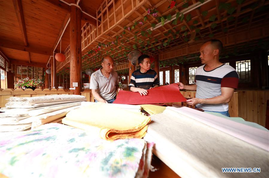 Wang Xingwu (C), a papermaker, talks with other craftsmen about papermaking skills at a workshop in Shiqiao Village of Danzhai County, southwest China\'s Guizhou Province, April 24, 2019. Wang Xingwu, 53, a national intangible cultural heritage inheritor in papermaking, learned the papermaking technique from his family as a child. Besides exerting the old papermaking technique to its full potential, Wang keeps raising product quality and improving the making procedure. With the involvement of plants in the papermaking process, he has created more than 160 kinds of patterned papers and paper crafts. He also develops a kind of handmade white paper more suitable for writing calligraphy and painting. (Xinhua/Huang Xiaohai)