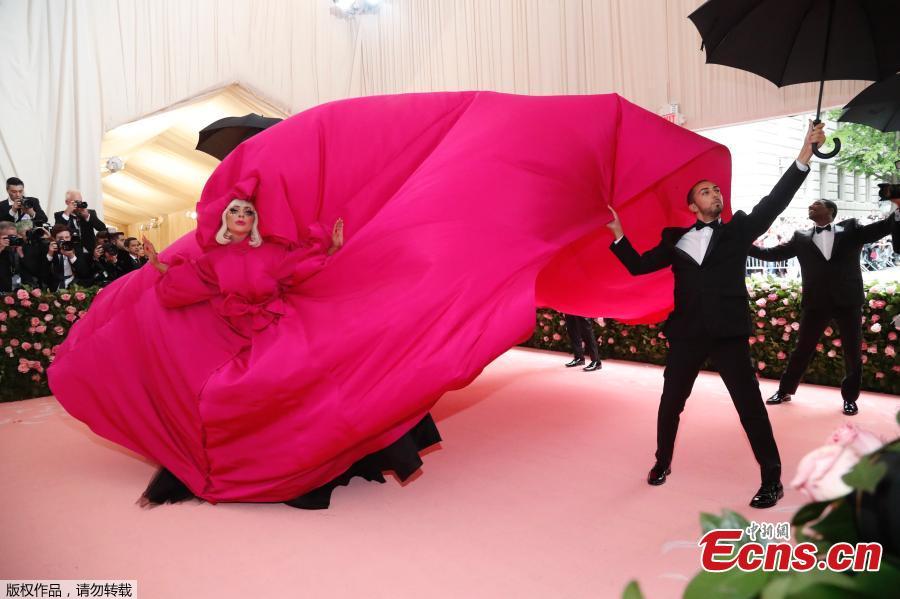 Lady Gaga arrives in a fuchsia dress with an enormous train and an entourage of umbrella-holding, suit-wearing men to handle it at the Metropolitan Museum of Art on May 6, 2019, in New York.  (Photo/Agencies)

The red carpet was rolled out and celebrities made grand entrances with outfits based on their interpretation of the theme, “Camp: Notes on Fashion”, at the 2019 Met Gala in New York City on Monday.