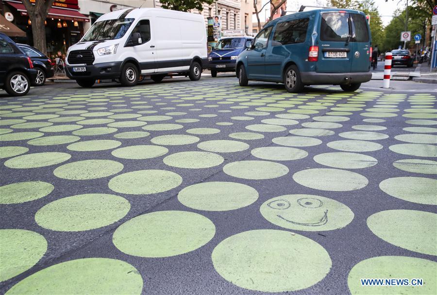 Vehicles drive across a green dotted street area in Bergmann Street of Kreuzberg, southern Berlin, Germany, on May 7, 2019. The green dots, part of new street signals in Berlin, are applied as a trial at a part of Bergmann Street with a speed limit of 20km/h, aiming to induce vehicles to drive with restricted speed. (Xinhua/Shan Yuqi)