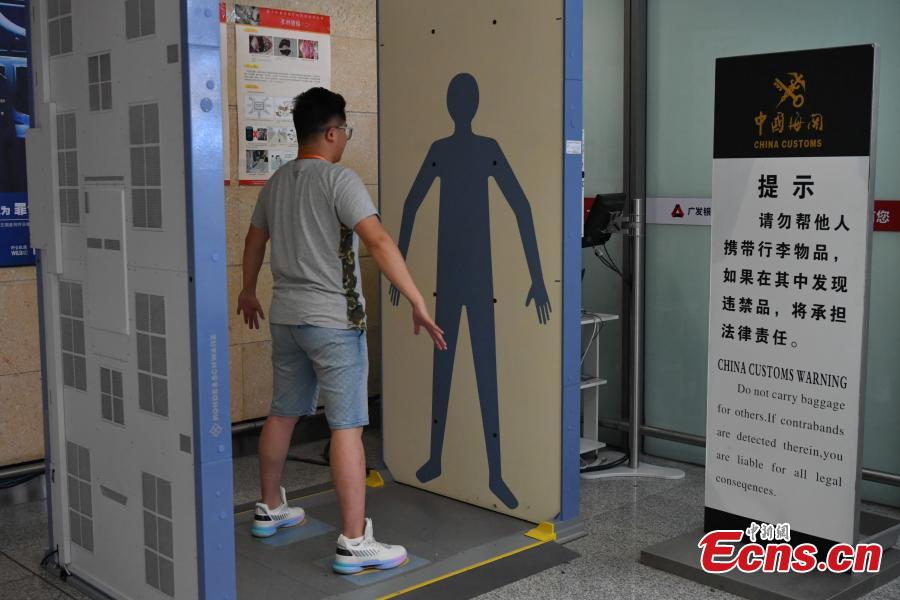 A man demonstrates a safety check using a millimeter wave scanner at the Changshui International Airport in Kunming City, Yunnan Province, May 8, 2019. Kunming Customs showcased endangered species and wildlife products seized by staff at the airport. (Photo: China News Service/Ren Dong)