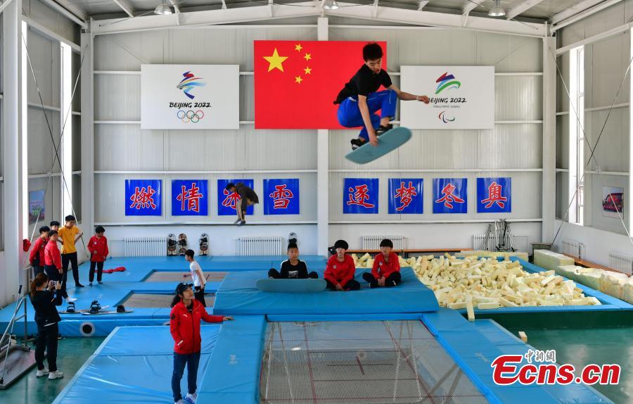 A student practices snowboarding under the instruction of coach Sun Zhifeng (with blue hat) at the Youth Winter Olympic Sports School, or Xuanhua No. 2 Middle School, in Zhangjiakou, Hebei Province, May 9, 2019. The school established in 2015 is the only of its kind to specialize on training of Winter Olympic sports in China. The school has recruited more than 1,200 students, including 200 trained to be competitive skiers. Located some 200km northwest of Beijing, Zhangjiakou will host snowboarding, freestyle skiing, cross-country skiing, ski jumping, Nordic combined and biathlon competitions during the 2022 Winter Games. (Photo: China News Service/Zhai Yujia)