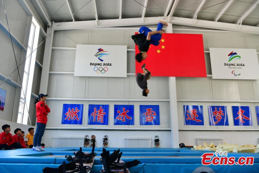 A student practices snowboarding under the instruction of coach Sun Zhifeng (with blue hat) at the Youth Winter Olympic Sports School, or Xuanhua No. 2 Middle School, in Zhangjiakou, Hebei Province, May 9, 2019. The school established in 2015 is the only of its kind to specialize on training of Winter Olympic sports in China. The school has recruited more than 1,200 students, including 200 trained to be competitive skiers. Located some 200km northwest of Beijing, Zhangjiakou will host snowboarding, freestyle skiing, cross-country skiing, ski jumping, Nordic combined and biathlon competitions during the 2022 Winter Games. (Photo: China News Service/Zhai Yujia)