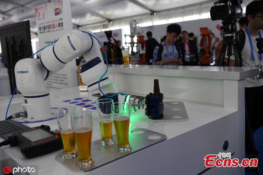 A robot performs tasks including writing calligraphy with a brush, cooking, and delivering beer after opening a bottle all on its own during the 6th China Robotop Summit in Ningbo City, East China\'s Zhejiang Province, May 9, 2019. According to its official website, the summit aims to promote the application of robots in intelligent manufacturing. (Photo/IC)