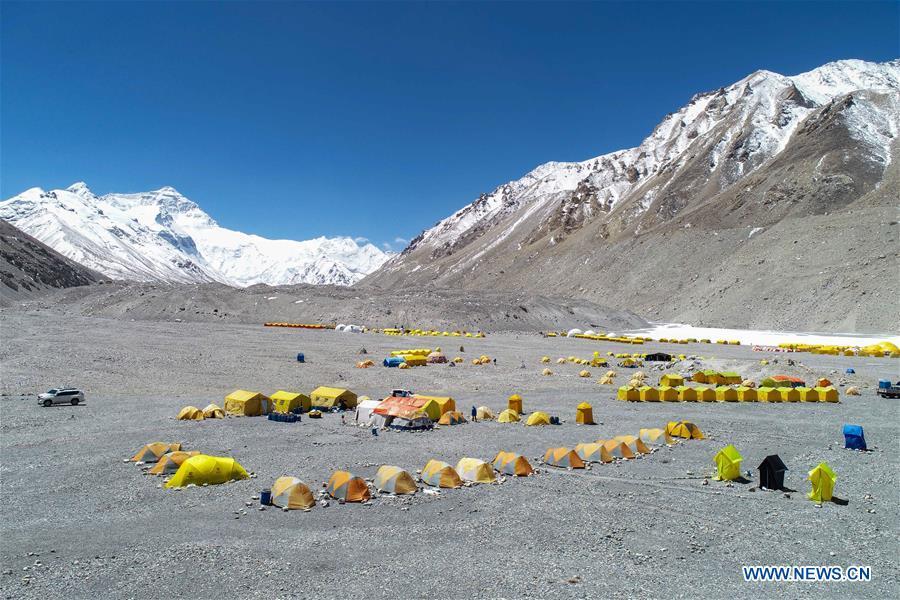 Aerial photo taken on April 25, 2019 shows the base camp of the northern face of Mount Qomolangma in southwest China\'s Tibet Autonomous Region. Every year, for a few weeks, hundreds of climbers and supporting personnel come to the base camp of the northern face of Mount Qomolangma, trying to reach the summit of the tallest and most famous mountain in the world. Before starting climbing, they need to hike several times between elevations from 5,000 meters to 7,000 meters, giving their bodies some time to adapt. When this process is over, it\'s all up to the weather. The base camp is a popular place to wait for the window. Among the six camps on the northern face, the base camp at an altitude of 5,200 meters is the furthest cars can reach and therefor the most equipped. Besides food and accommodation, climbers can also enjoy tea and massage. They can also play football on perhaps the highest field. There\'s even a simple gym in the camp. Environmental protection is a priority here. Garbage sacks are given to each climbing team. Special containers are put in every camp to collect trash and sewage. The collected trash must be treated 100 kilometers away, and the only road is a zigzagging track. It is not trucks, but yaks that are generally used to make the journey. Actually yaks are vital on the mountain. Beyond the base camp, yak is the only reliable transport. (Xinhua/Sun Fei)