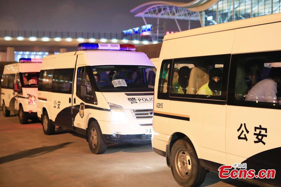 Police escort suspects caught in a social network and telecommunication fraud bust as they arrive at Pudong International Airport in Shanghai, May 14, 2019. Police detained the 57 suspects in Danzhou City of South China’s Hainan Province and then transported them to Shanghai as investigations continue.  (Photo: China News Service/Yin Liqin)