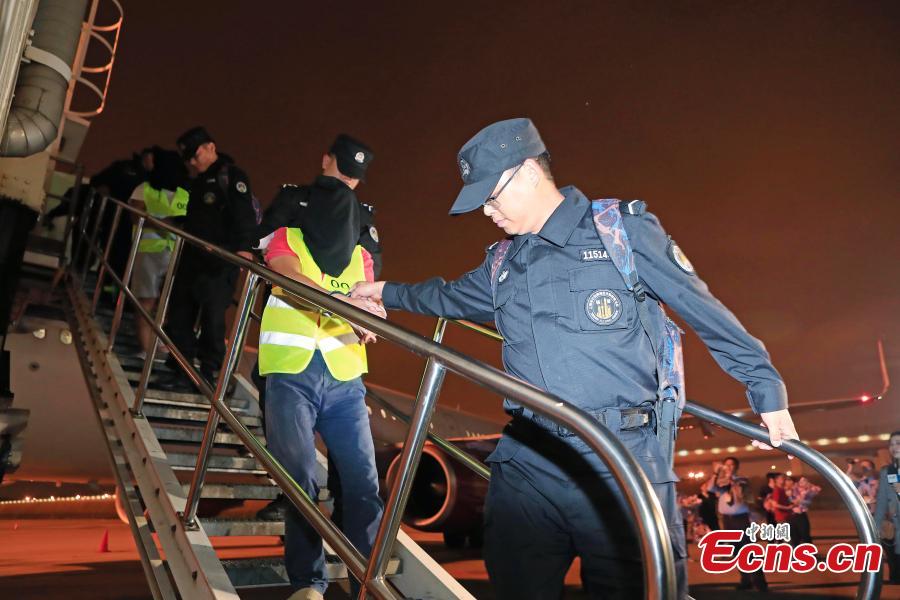 Police escort suspects caught in a social network and telecommunication fraud bust as they arrive at Pudong International Airport in Shanghai, May 14, 2019. Police detained the 57 suspects in Danzhou City of South China’s Hainan Province and then transported them to Shanghai as investigations continue.  (Photo: China News Service/Yin Liqin)