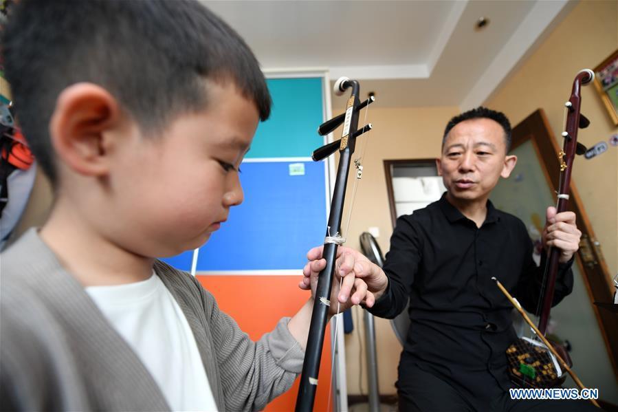 Erhu performer Zhang Zhijun (R) instructs his student in Lanzhou, northwest China\'s Gansu Province, May 13, 2019. Erhu, sometimes known as the Chinese violin or Chinese two-stringed fiddle, is a Chinese traditional two-stringed bowed musical instrument. It is used as a solo instrument as well as in small ensembles and large orchestras. Erhu, traced back to ancient Chinese Tang dynasty (618-907), is now used in both traditional and contemporary music arrangements, such as in pop, rock and jazz. The famous solo pieces include Er Quan Ying Yue (Two Springs Reflecting the Moon) by Abing and Sai Ma (Horse Race) by Huang Haihuai. (Xinhua/Fan Peishen)