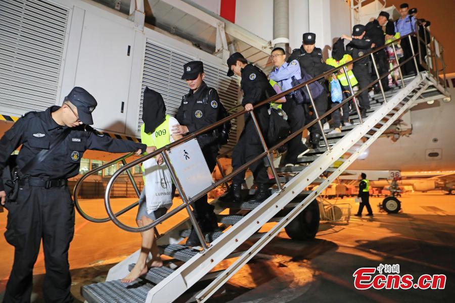 Police escort suspects caught in a social network and telecommunication fraud bust as they arrive at Pudong International Airport in Shanghai, May 14, 2019. Police detained the 57 suspects in Danzhou City of South China’s Hainan Province and then transported them to Shanghai as investigations continue.  (Photo: China News Service/Yin Liqin)
