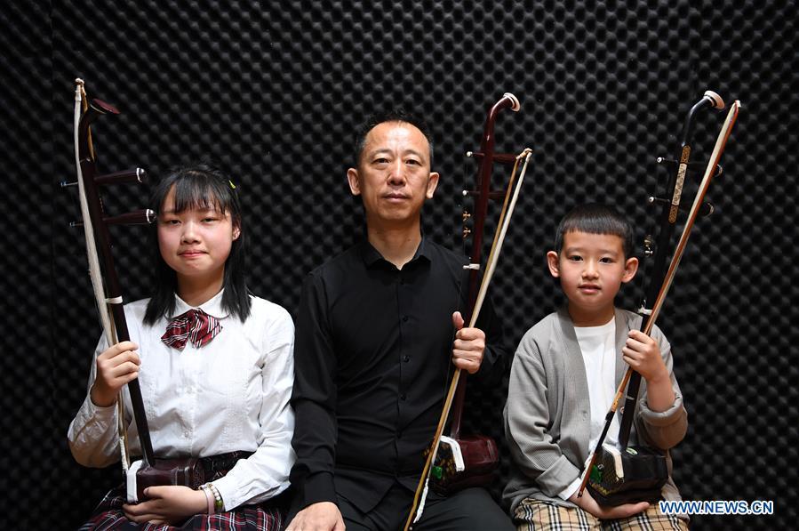 Erhu performer Zhang Zhijun (C) poses for a group photo with his students in Lanzhou, northwest China\'s Gansu Province, May 13, 2019. Erhu, sometimes known as the Chinese violin or Chinese two-stringed fiddle, is a Chinese traditional two-stringed bowed musical instrument. It is used as a solo instrument as well as in small ensembles and large orchestras. Erhu, traced back to ancient Chinese Tang dynasty (618-907), is now used in both traditional and contemporary music arrangements, such as in pop, rock and jazz. The famous solo pieces include Er Quan Ying Yue (Two Springs Reflecting the Moon) by Abing and Sai Ma (Horse Race) by Huang Haihuai. (Xinhua/Fan Peishen)