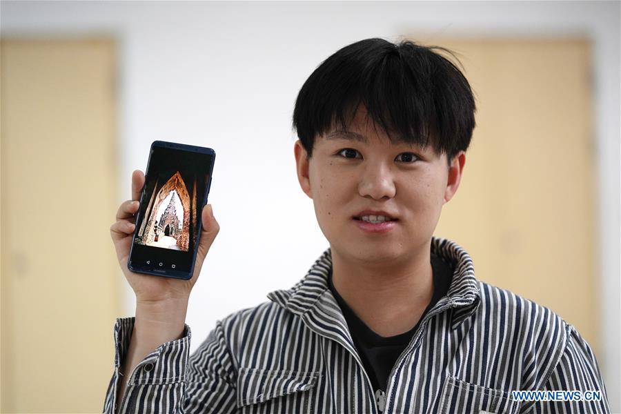 Ratjirot Aekkawat shows his photo of the historical site of Ayutthaya Dynasty in Beijing, capital of China, May 12, 2019. Ratjirot Aekkawat is of mixed blood from China and Thailand. He came to study in China as a junior student and now he is a postgraduate student of the Peking University. He always talks about his experience in China with relatives and friends. He has witnessed the development of China in recent years, during which the environment and local governments\' working efficiencies have been greatly improved. Chinese and Thai cultures are influenced with each other. Many Thai people celebrate the Spring Festival every year and lots of Chinese go to Thailand for tourism. The photo of the historical site of Ayutthaya Dynasty taken by Ratjirot Aekkawat will be displayed in a photographic exhibition \