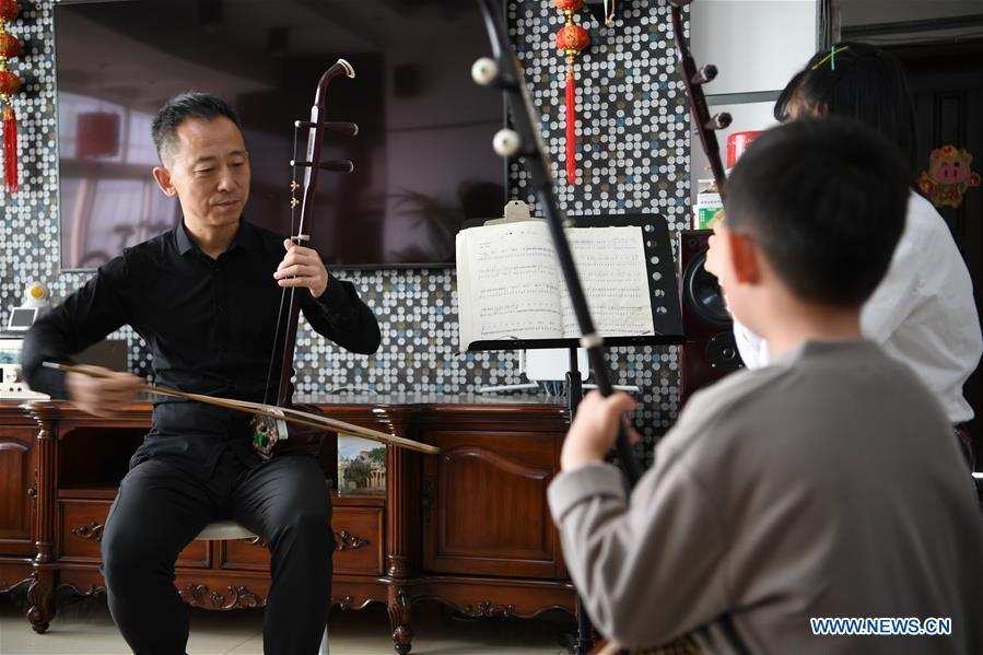 Erhu performer Zhang Zhijun (L) instructs his students in Lanzhou, northwest China\'s Gansu Province, May 13, 2019. Erhu, sometimes known as the Chinese violin or Chinese two-stringed fiddle, is a Chinese traditional two-stringed bowed musical instrument. It is used as a solo instrument as well as in small ensembles and large orchestras. Erhu, traced back to ancient Chinese Tang dynasty (618-907), is now used in both traditional and contemporary music arrangements, such as in pop, rock and jazz. The famous solo pieces include Er Quan Ying Yue (Two Springs Reflecting the Moon) by Abing and Sai Ma (Horse Race) by Huang Haihuai. (Xinhua/Fan Peishen)