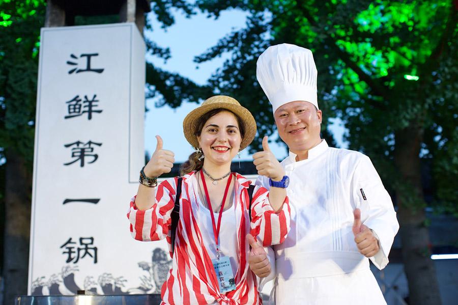 A tourist poses with a chef at a tasting event for fish from the Qiantang River in Hangzhou. (Photo provided to China Daily)