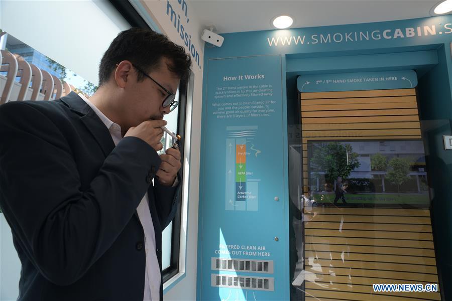 A man smokes inside a smoking cabin in Singapore on May 21, 2019. Singapore\'s first smoking cabin was launched on Tuesday. The air-conditioned cabin measures 4.8 square metres in size, that allows a maximum of 10 users at one time, and uses 3 filters to filter the air inside. (Xinhua/Then Chih Wey)
