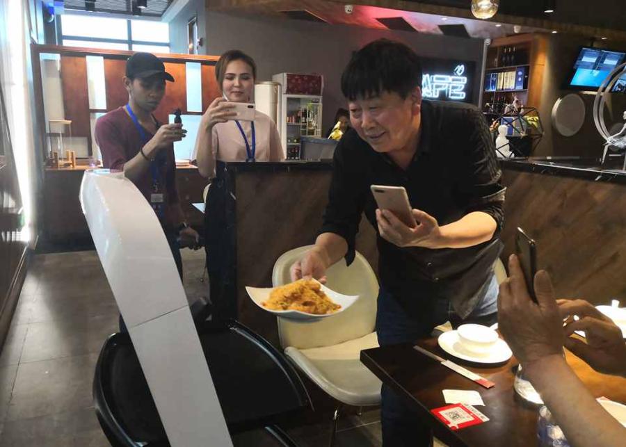 A customer takes food from a robot at the X Future Restaurant. (Photo/People\'s Daily Online)