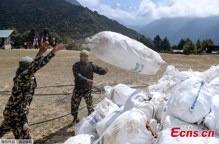 Nepali Army personnel throw bags of waste collected from the Mount Everest at Namche Bazar, on May 27, 2019, before it is transported to Kathmandu to be recycled. Nepal government sent a dedicated clean-up team to Mount Everest this season with a target to bring back 10,000 kilograms of trash in an ambitious plan to clean the world\'s highest rubbish dump. (Photo/Agencies)