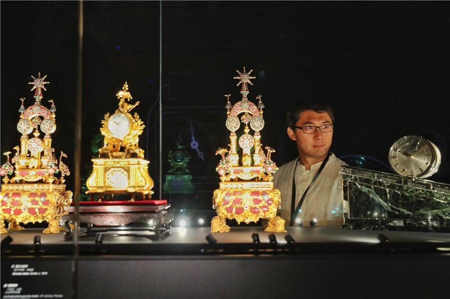 A visitor views top-tier timepieces at the exhibition. (Photo provided to China Daily)

According to Rainero, a passion for Chinese culture became a trend in the West during the 1920s, and fashion brands were quick to respond to the ever-growing demand. Chinese aesthetics and motifs influenced not only the design of jewelry sets, watches and clocks, but also the workmanship of specific materials, nourishing an entire process of creation.

That period is also reflected in the section Chinese Inspirations at the exhibition through artifacts made of typical materials and patterns rooted in the traditions of Chinese culture.

For instance, the Carp clock from 1925 was made of a piece of carved ancient jade depicting two fishes swimming in the waves. Carp is appreciated for its courage and tenacity in Chinese culture, allowing it to swim upstream and change into a dragon.

Elements of Chinese culture seems to be ubiquitous in European upper-class life during this era, which are reflected in a range of exhibits, from a lacquer bridge case that was once owned by the well-known Rothschild family, to a platinum brooch and a vanity case featuring dragon motifs.

As China continues to develop rapidly both economically and culturally, Vigneron says he believes that it is important to remind people of their own traditions through familiar artifacts.